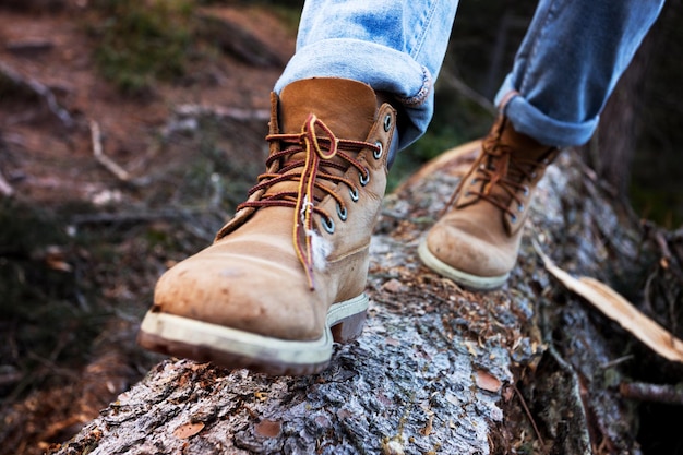 Wanderschuhe Nahaufnahme. Mädchentouristin tritt auf einen Baumstamm