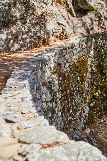 Wanderweg mit riesiger Steinmauer entlang von Klippen