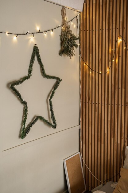 Warm leuchtende Girlandenlichter, die an Holzschienen an der Wand hängen Weihnachtssternkranz Minimalistisches, modernes skandinavisches Design im Hygge-Stil