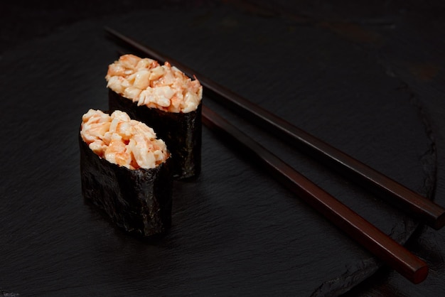 Warme Brötchen mit Thunfisch-Lachs-Aal-Tobiko-Kaviar-Nori-Reisgurke auf schwarzem Hintergrund