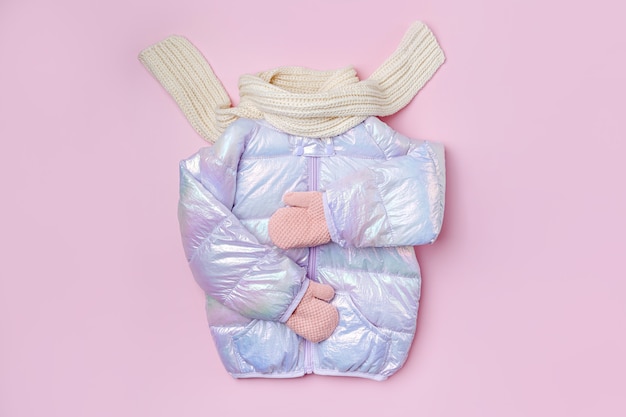 Warme Daunenjacke für Kinder mit Schal auf rosa Hintergrund. Stylische Kinderoberbekleidung. Wintermode-Outfit