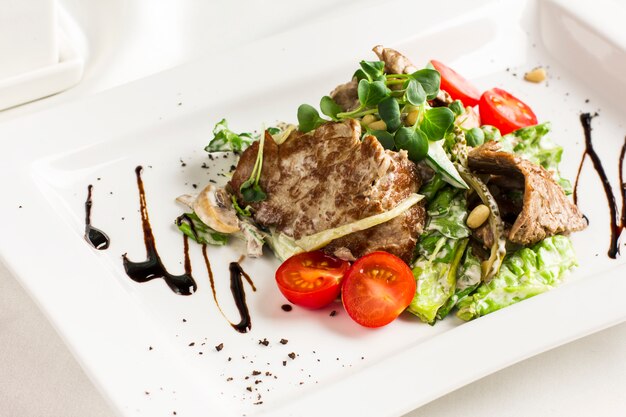 Warmer Salat mit Fleisch, Pilzen, Kirschtomaten, Pinienkernen und Kräutern