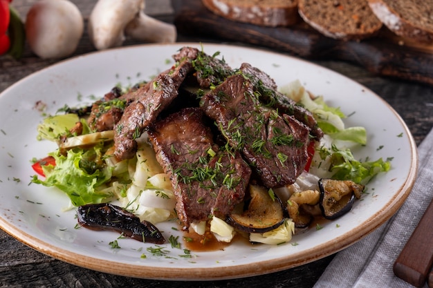 Warmer Salat mit gebratenem Kalbfleisch und Gemüse auf einem Teller