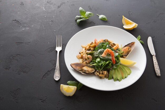 Warmer Salat mit gegrillten Meeresfrüchten flach. Draufsicht auf Teller mit Mischung aus gebratenen Garnelen, Muscheln und Tintenfisch, Restaurantbedienung, Kopierraum