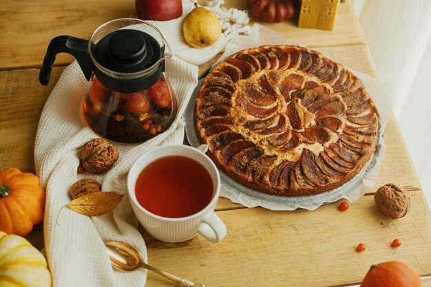 Warmer Tee in stilvoller Tasse auf rustikalem Tisch mit frisch gebackenem Apfelkuchen mit Zimt Hygge nach Hause