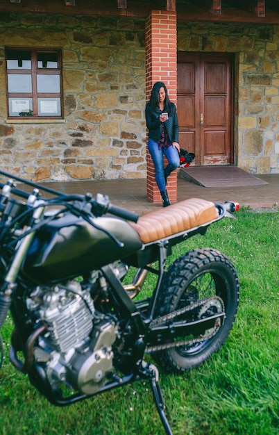 Wartende Frau, die das Handy mit benutzerdefiniertem Motorrad betrachtet