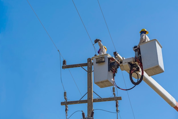 Wartung von Elektrikern arbeitet mit Hochspannungsstrom an der hydraulischen Schaufel