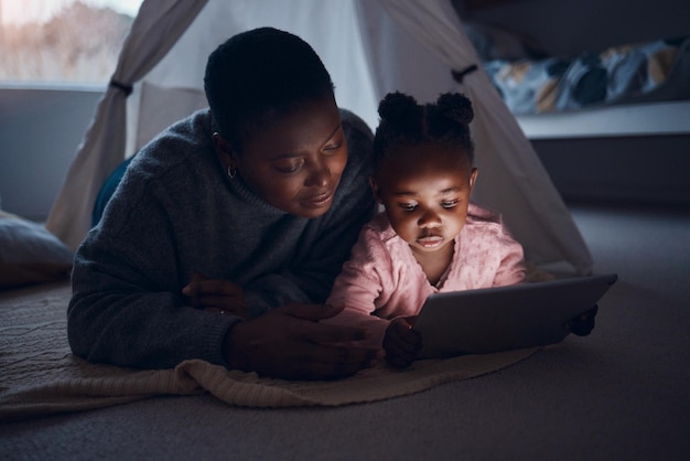 Was wirst du Mama vorlesen Aufnahme einer Mutter, die mit ihrer Tochter Gutenachtgeschichten auf einem digitalen Tablet liest