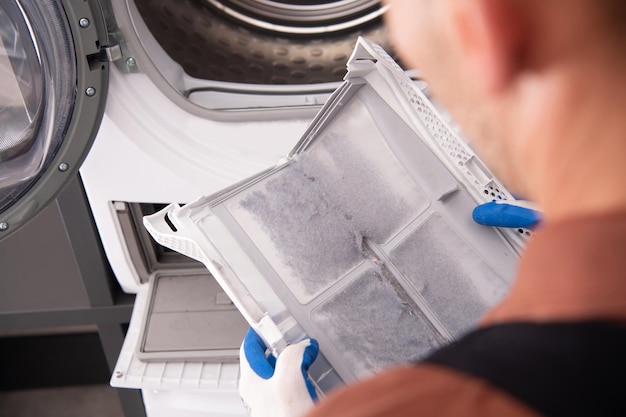 Foto wasch- und trocknungsmaschinenfilter durch schmutzfilter abgedeckt reinigung durch haushaltsgeräte-techniker