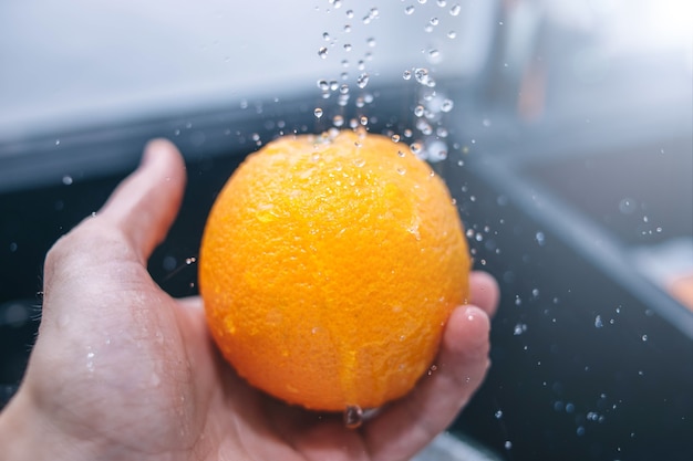 Waschen einer Orange unter fließendem Wasser nasses Obst