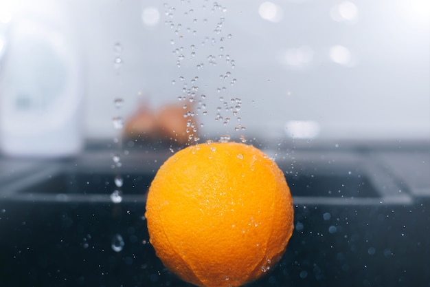 Waschen einer Orange unter fließendem Wasser nasses Obst