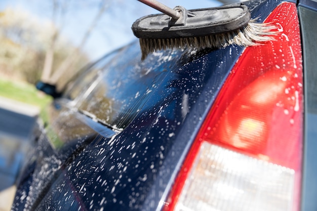 Waschen Sie das Auto von Hand mit einer Bürste mit Schaum