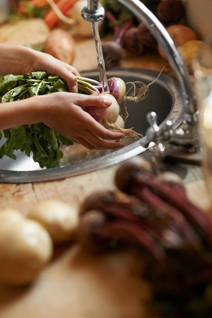 Foto waschen von gemüse und händen in der küche für eine gesunde lebensmittelhygiene und kochen oder zubereiten durch spülbecken person mit wasserflüssigkeit und zwiebeln für das abendessen oder das organische vegane und vegetarische mittagessen