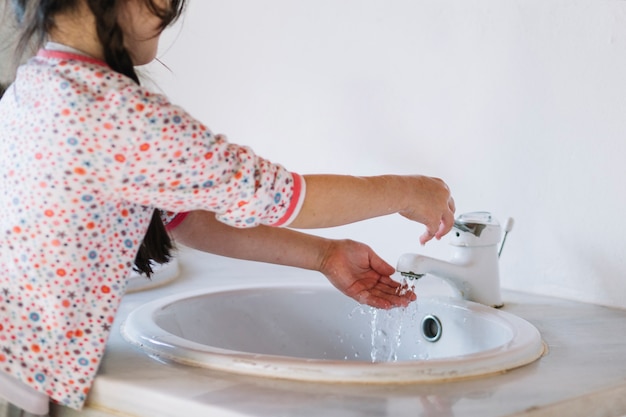 Waschende Hand des Mädchens im Badezimmer