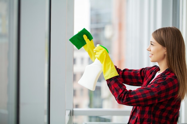 Waschendes Fenster der jungen Asiatin mit Schwamm