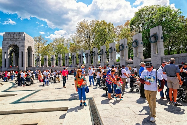 Washington dc, eua - 2 de maio de 2015: turistas e veteranos de guerra e guardiões da organização sem fins lucrativos honor flight no memorial nacional da segunda guerra mundial, national mall. arco do pacífico à esquerda