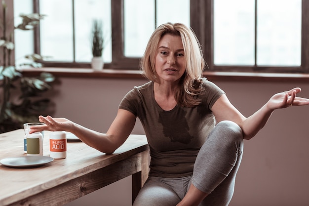 Wasser auf T-Shirt. Betrunkene blonde Frau verschüttet Wasser auf T-Shirt, während sie Depressionen hat