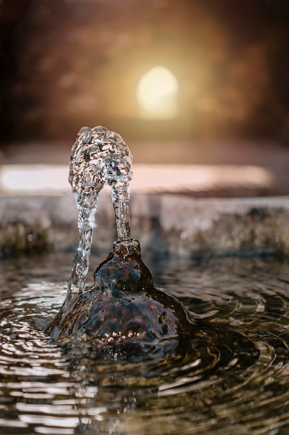 Wasser aus Felsenbrunnen mit Licht im Hintergrund