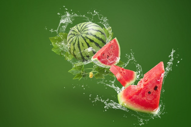 Wasser, das an spritzt Geschnitten von der Wassermelone auf grünem Hintergrund