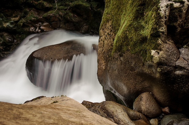 Wasser des Moutain-Flusses, das vom Felsen in der Nähe der moosbedeckten Steine in den Aphrodite-Bädern in Georgia fällt