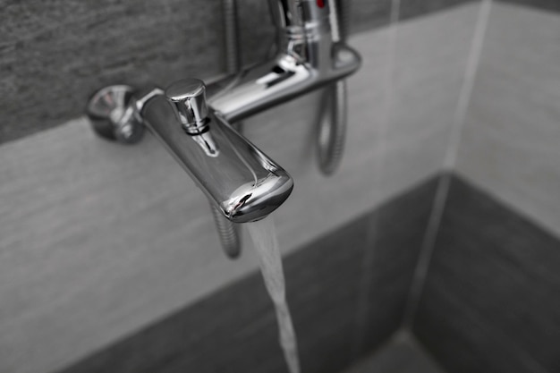 Wasser fließt aus dem Mischer Moderner Designer-Hahn und Dusche im Badezimmer