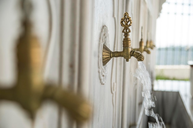 Foto wasser fließt aus einem goldenen wasserhahn in einer moschee