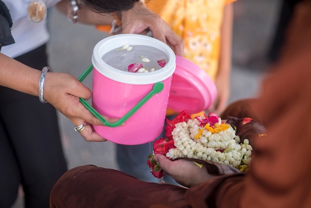 Wasser im Wasserschöpflöffel mit buntem Blumenuntersatz für Songkran-Festival