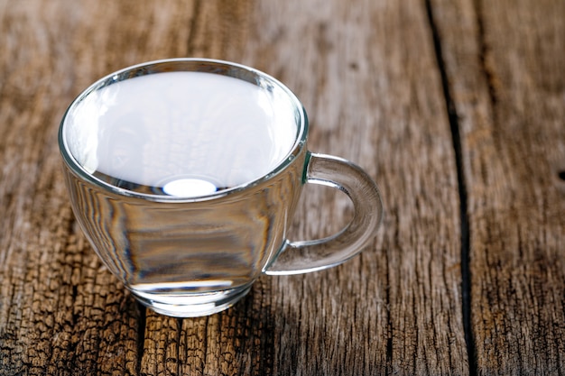 Wasser in der Tasse auf hölzernen Hintergrund