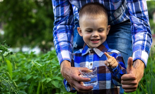 Wasser in einem Glas in den Händen eines Kindes und eines Vaters. Natur.