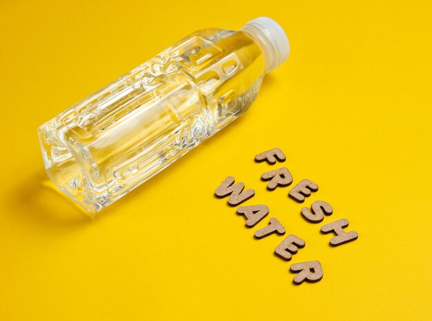 Wasser in Flaschen auf gelber Oberfläche mit den Worten Süßwasser.