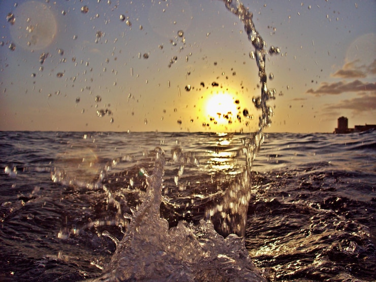 Foto wasser spritzt bei sonnenuntergang auf dem strand gegen den himmel