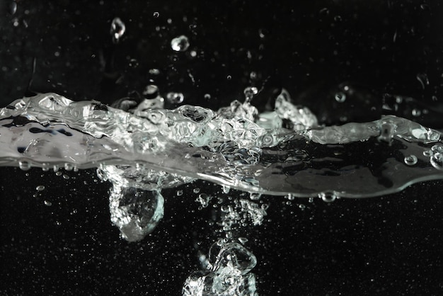 Wasser spritzt, wenn es in das Aquarium gegossen wird, schwarzer Hintergrund.