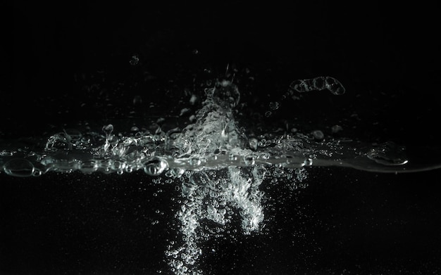 Wasser spritzt, wenn es in das Aquarium gegossen wird, schwarzer Hintergrund