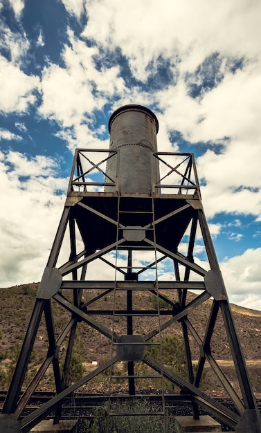 Wasserbehälter in der Eisenstruktur mit dem Himmel und dem Berg