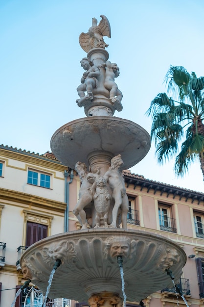 Wasserbrunnen auf der Plaza de la Constitucion der Stadt Malaga und ihren wunderschönen Palmen, Andalusien. Spanien