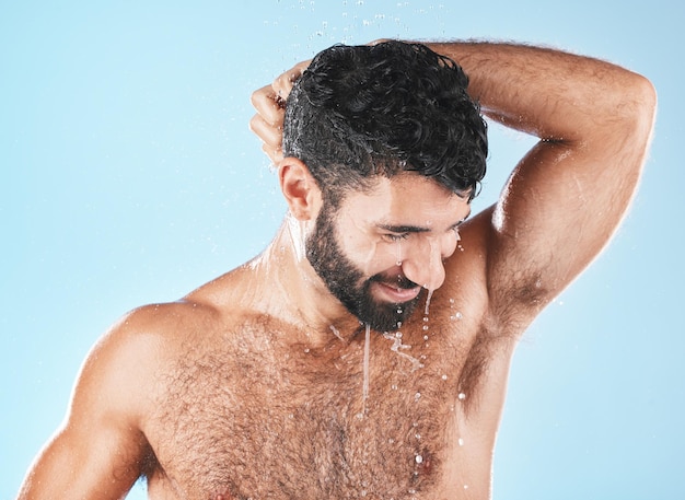 Wasserdusche und ein Mann, der Haare mit Shampoo im Studio auf blauem Hintergrund für Schönheit oder Hygiene wäscht Haarreinigung oder Behandlung mit einem hübschen Mann, der im Badezimmer nass ist, während er zur Haarpflege badet