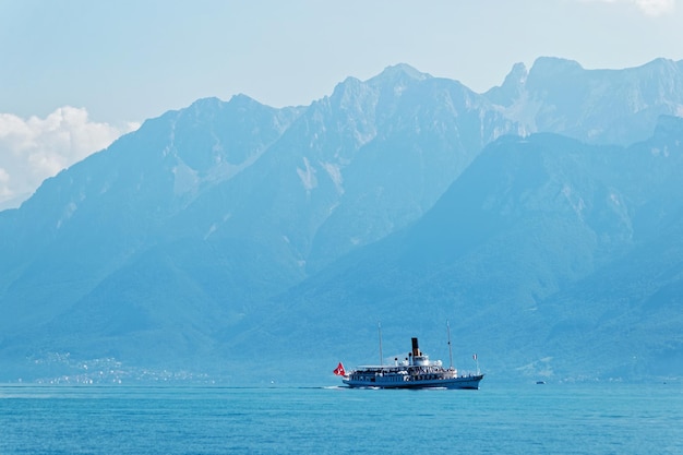 Wasserfähre mit Schweizer Flagge, im Genfersee am Ouchy-Damm in Lausanne, Schweiz. Leute an Bord