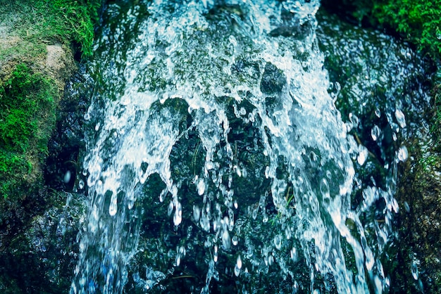 Wasserfall auf den Steinen mit grünem Moos getönt