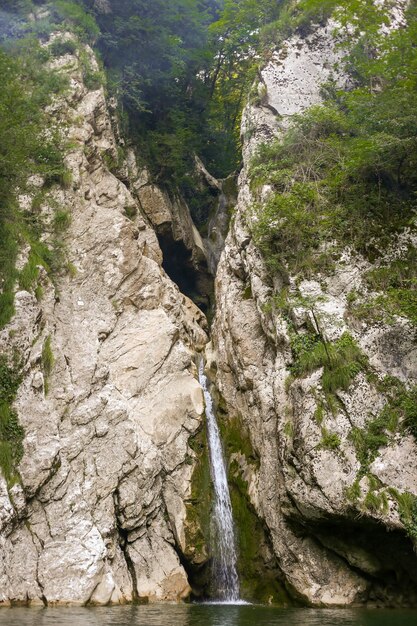 Wasserfall in einer Felsspalte zwischen den Felsen hinter den Bäumen Agur-Wasserfälle in Sotschi