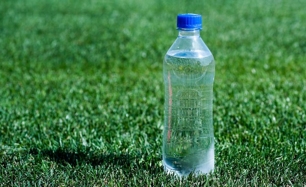 Wasserflasche auf grünem Gras, Sport und Fitness, gesundes Getränk, globaler Umweltschutz, Plastikmüll, muss recycelt werden, frisch und sauber, durstig, reines, natürliches Trinken, mineralische Vitamine