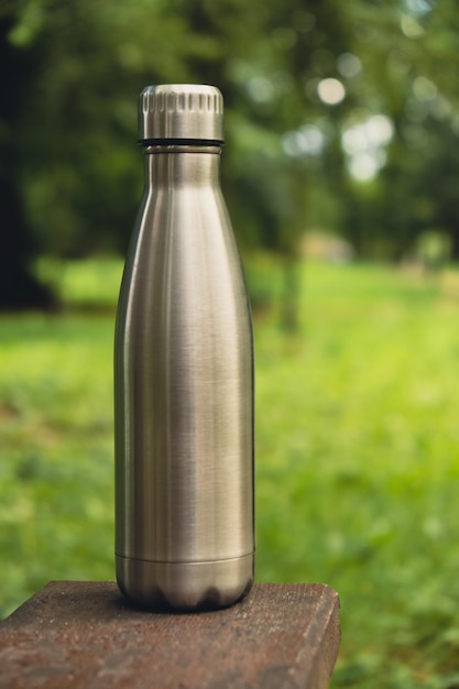 Foto wasserflasche aus wiederverwendbarem stahl thermo-wasserflasche auf holzbank nachhaltiger lebensstil aus kunststoff