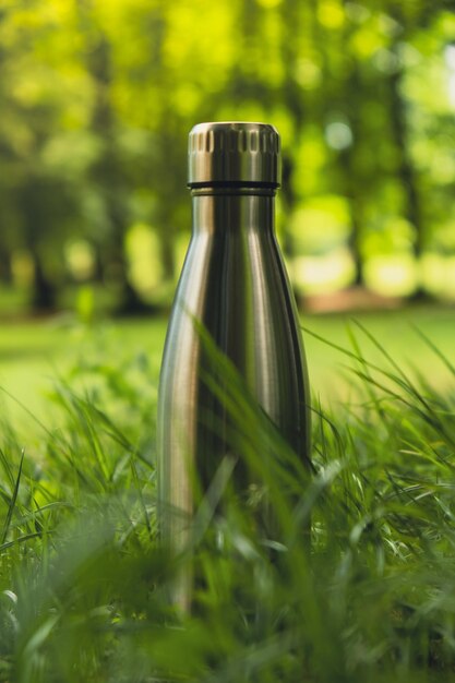Foto wasserflasche mit wiederverwendbarer stahlthermo-wasserflasche auf grünem gras nachhaltiger lebensstil plastikfrei
