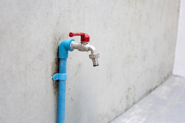 Wasserhahn auf Zementwandhintergrund.