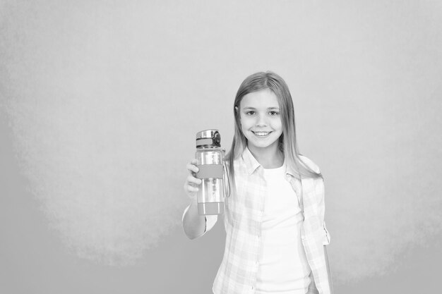 Foto wasserhaushalt-konzept gesund und hydratisiert pädiatrische störungen des wasserhaushalts mädchen kümmert sich um gesundheit und wasserhaushalt kind mädchen lange haare hat wasserflasche kind halten flasche blauen hintergrund