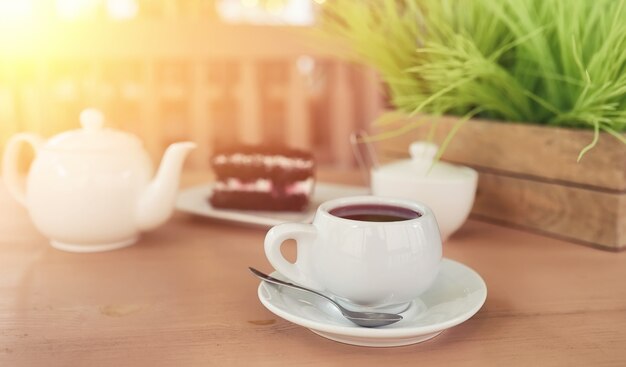 Wasserkocher mit einem Getränk und Dessert im Straßencafé. Tee in der Wasserkochertasse auf dem Tisch. Frühstück mit Tee und Kuchen im Café.