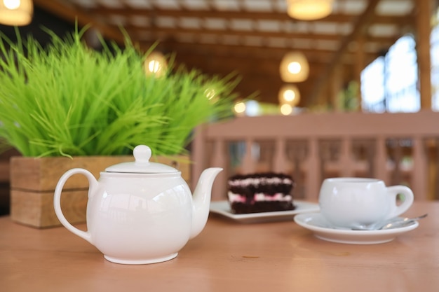 Wasserkocher mit Getränk und Dessert im Straßencafé. Tee in der Wasserkochertasse auf dem Tisch. Frühstück mit Tee und Kuchen im Café.