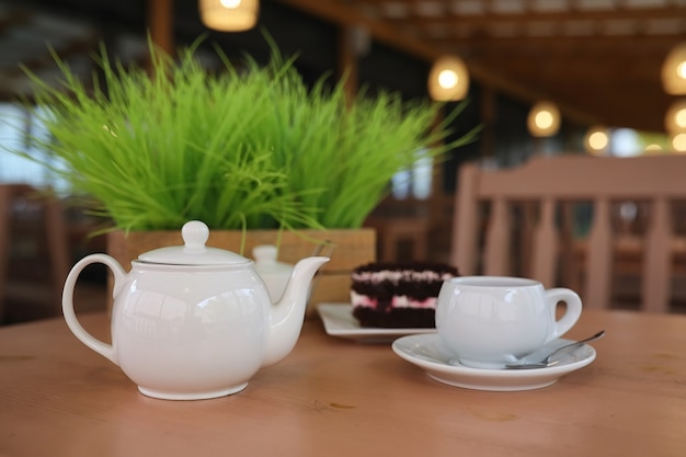 Wasserkocher mit Getränk und Dessert im Straßencafé. Tee in der Wasserkochertasse auf dem Tisch. Frühstück mit Tee und Kuchen im Café.