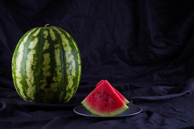 Wassermelone auf schwarzem Tuch Ganze Wassermelone mit dunklem Hintergrund Gesundes Essen für Veganer