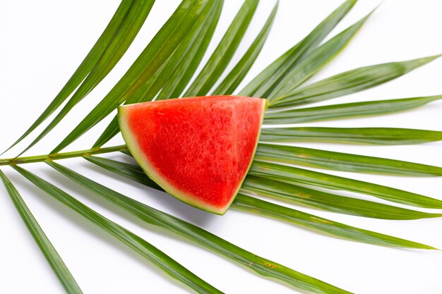 Wassermelone auf tropischen Palmblättern auf weißer Oberfläche