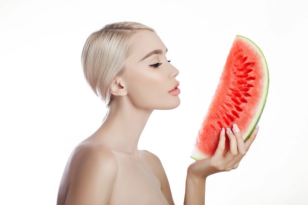 Wassermelone in den Händen der Frau, säubern glatte Haut des Körpers und des Gesichtes. Blondes Mädchen im Sommer eine Wassermelone in den Händen des Gesichtes halten. Anti-Falten- und Anti-Aging-Behandlung der Haut, natürliche Anti-Aging-Kosmetik